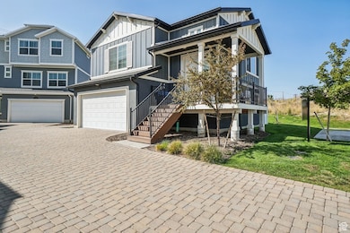 View of front of house with an attached garage, decorative driveway, board and batten siding, stairs, and a front yard