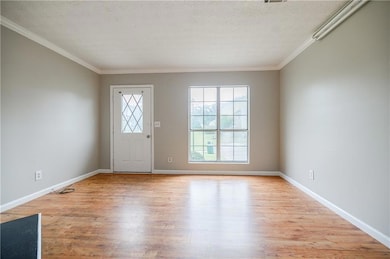 Entryway with crown molding, light wood-style floo