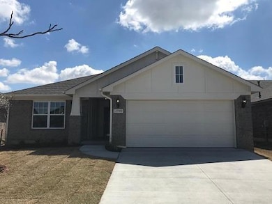 View of front of property with brick siding, an attached garage, and driveway