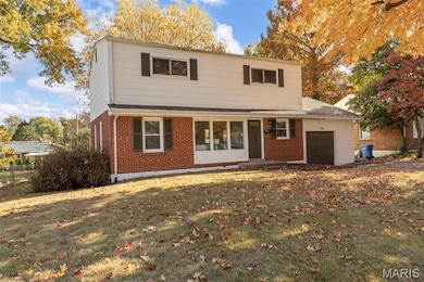 View of front of home featuring a front lawn, brick siding, and a garage