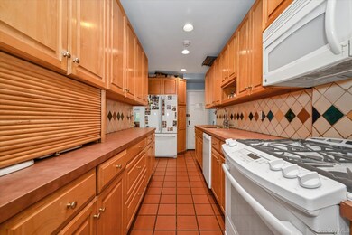 Kitchen featuring white appliances, dark tile patterned floors, recessed lighting, and tasteful backsplash