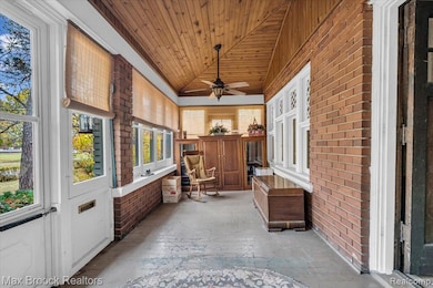 Sunroom / solarium featuring brick wall, wood ceiling, and vaulted ceiling
