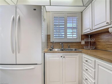 Kitchen with freestanding refrigerator, a sink, white cabinets, and decorative backsplash
