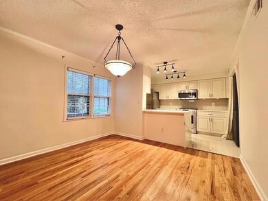 Kitchen with stainless steel appliances, white cabinets, a textured ceiling, light wood-type flooring, and light countertops
