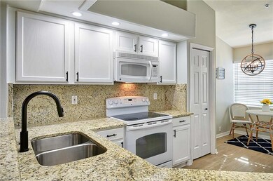 Kitchen with white cabinets, white appliances, sin