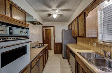 Kitchen with wooden walls, a textured ceiling, wai