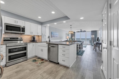 Kitchen featuring appliances with stainless steel finishes, a peninsula, a sink, wooden ceiling, and white cabinetry