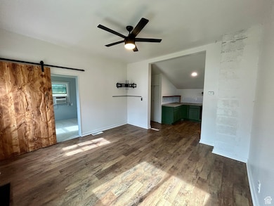 Unfurnished living room featuring dark wood-style floors, a barn door, ceiling fan, and cooling unit
