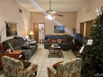 Living room featuring light tile patterned floors, a ceiling fan, and vaulted ceiling