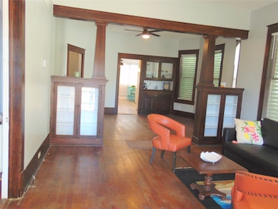 Original hardwood floors and china cabinets in living room and dining room beyond.