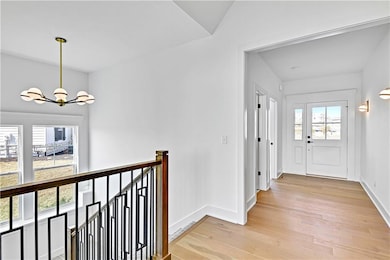 Corridor with a wealth of natural light, light wood-style flooring, and a chandelier