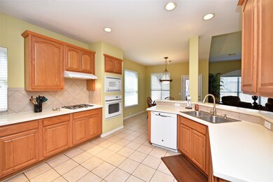 Hone your culinary skills in this immaculate kitchen. Whether looking out the kitchen window into the yard or watching the kids in the family room, the chef will never be far from the action. This bright space boasts a double basin stainless steel sink with updated faucet, tile flooring and recessed lighting.