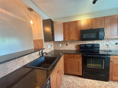 Kitchen with black appliances, a sink, backsplash