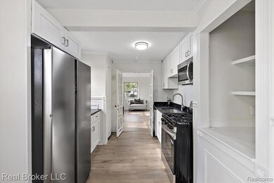 Kitchen with stainless steel appliances, white cabinets, light wood finished floors, crown molding, and open shelves