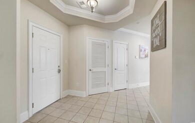 Entrance foyer with ornamental molding, light tile patterned floors, and a tray ceiling