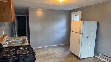 Kitchen with black range with electric cooktop, freestanding refrigerator, light wood finished floors, and a baseboard heating unit