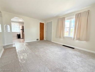 Living room with arched walkways and light colored carpet