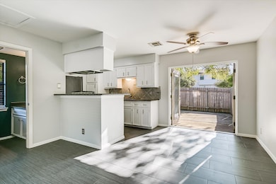 Kitchen with white cabinetry, decorative backsplash, plenty of natural light, and a peninsula