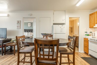 Dining room featuring ornamental molding, light wood finished floors, and an AC wall unit