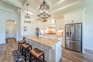 Kitchen with hanging light fixtures, stainless steel appliances, tasteful backsplash, hardwood / wood-style flooring, and an island with sink