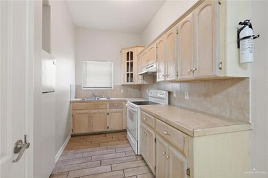 Kitchen with electric range, under cabinet range hood, light brown cabinets, and light countertops