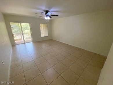 Empty room featuring ceiling fan and light tile pa