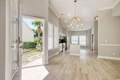 Entrance foyer with light wood LVP flooring, updated fixtures, ornamental molding, and recessed lighting.