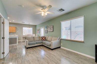 Living room featuring a ceiling fan, light wood-st