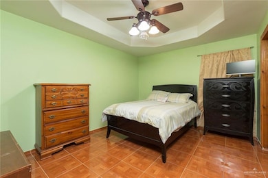 Primary Bedroom - This bedroom is painted a soothing green, creating a restful environment. The room includes a bed with a cushioned headboard and two large dressers for storage. A ceiling fan with classic light fixtures illuminates the room, adding comfort to the primary sleeping space.