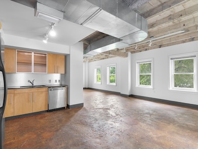 Kitchen featuring rail lighting, concrete floors, dishwasher, open floor plan, and freestanding refrigerator