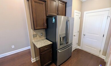 Kitchen with stainless steel refrigerator with ice dispenser, dark wood finished floors, backsplash, and dark brown cabinetry