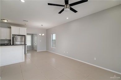 Kitchen with stainless steel fridge, dark countertops, baseboards, a ceiling fan, and white cabinetry