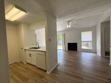 Kitchen with a fireplace, white cabinetry, dark wood-style flooring, a ceiling fan, and white dishwasher