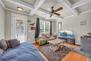 Living area featuring coffered ceiling, wood finished floors, healthy amount of natural light, ceiling fan, and baseboards
