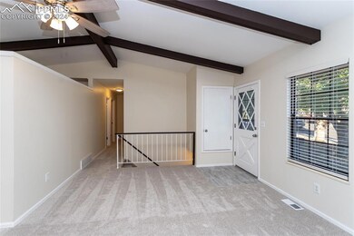 Empty room featuring light carpet, vaulted ceiling with beams, and ceiling fan