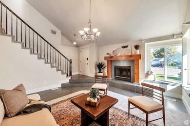 Living area featuring stairway, a tiled fireplace, lofted ceiling, tile patterned floors, and a chandelier