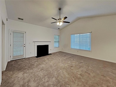 Unfurnished living room with ceiling fan, lofted ceiling, carpet floors, and a fireplace with flush hearth