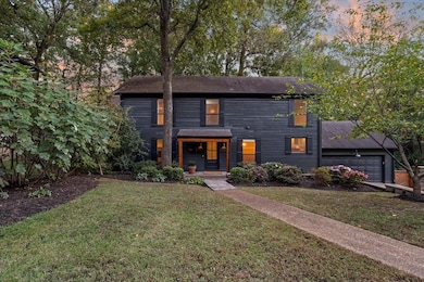 Evening view of front of home featuring a front yard and a garage