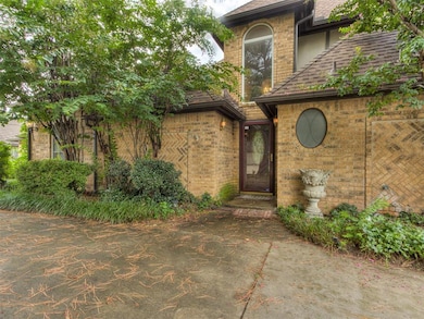 View of exterior entry with roof with shingles and brick siding