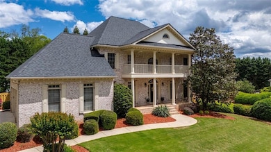 Aerial view highlights expansive front yard, mature landscaping, and the home’s prominent location in a quiet, established neighborhood.