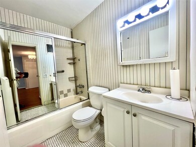 Bathroom featuring tile patterned flooring,  shower combination, vanity, and wallpapered walls