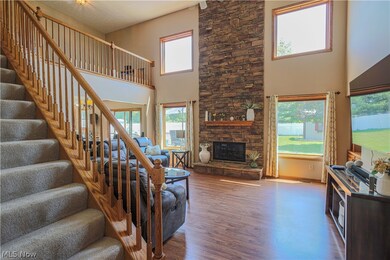 Living room with a towering ceiling, a stone fireplace, and hardwood / wood-style flooring