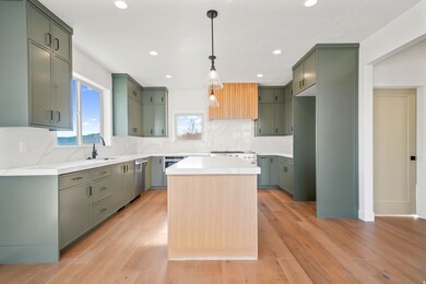 Kitchen featuring backsplash, green cabinetry, hanging light fixtures, light stone countertops, and a center island