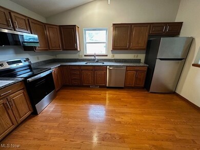 Kitchen featuring appliances with stainless steel finishes, lofted ceiling, and light wood finished floors