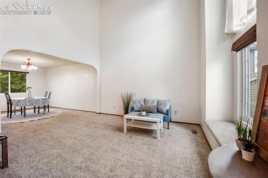 Sitting room featuring carpet flooring, arched walkways, a high ceiling, and a chandelier