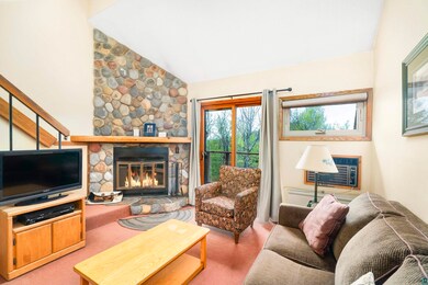 Carpeted living room with a stone fireplace, an AC