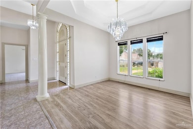 dining room with a chandelier, wood finished floors, decorative columns, and a tray ceiling