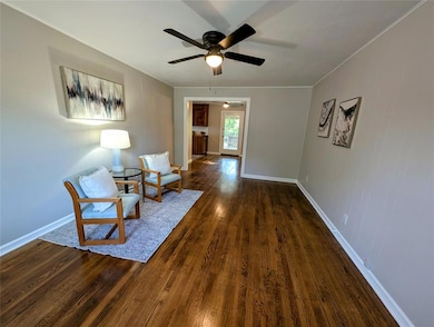Unfurnished room featuring ceiling fan, dark wood-style floors, baseboards, and ornamental molding