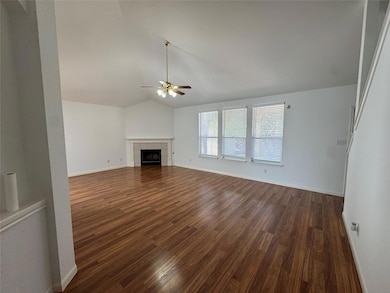 Unfurnished living room with lofted ceiling, dark wood-style flooring, ceiling fan, and a tiled fireplace