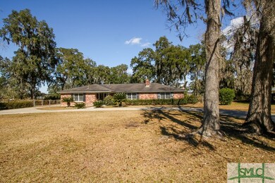 Front of home nestled amongst large, live oaks